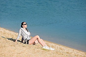 Summer active woman sit on beach sunset in fitness outfit