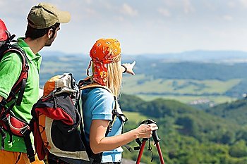 Young backpack couple with hiking poles beautiful panoramic view countryside