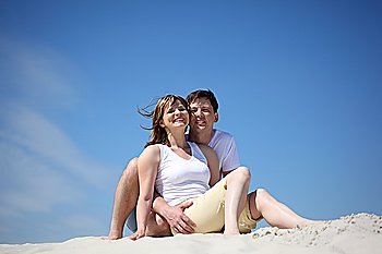 couple in white shirts sitting on sand