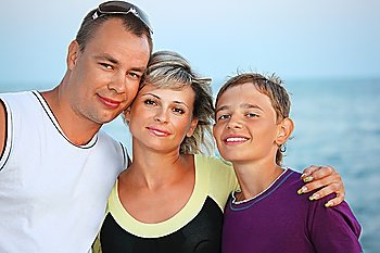 Happy family with smiling boy on beach in evening