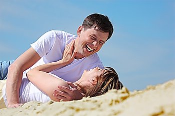 Laughing young pair lying on sand