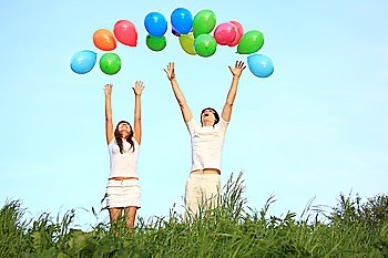 girl and  guy start multicoloured balloons in sky