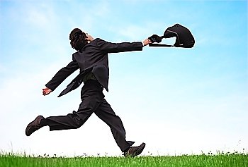 Businessman running on the meadow with bag