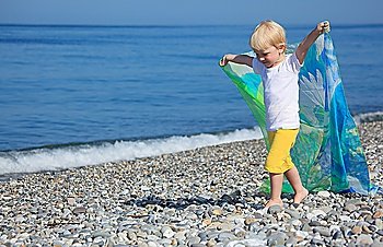 child with shawl goes on pebble beach