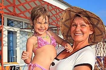 mature woman with little girl on hands outdoor, focus on grandmother