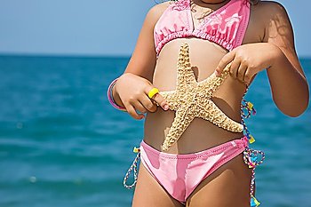 Body of little girl with starfish on beach