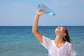 beautiful woman watering from bottle on seacoast, closed eyes