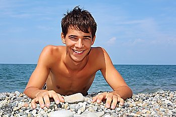 teenager boy lying on stony seacoast