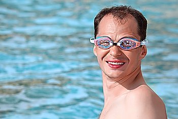 smiling young man in watersport goggles swimming in pool