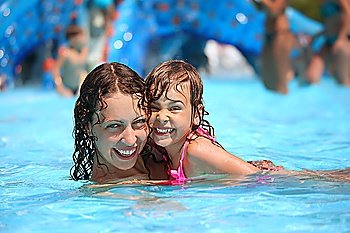 Smiling beautiful woman and little girl bathes in pool in aquapark