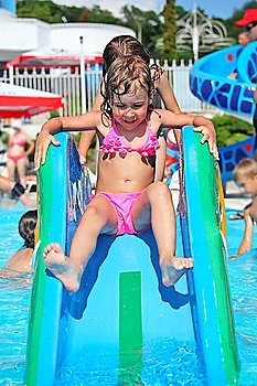 pretty little girl goes down on hill in aquapark of an entertaining complex