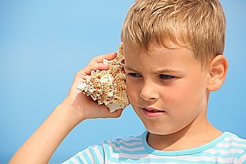 little boy with shell listening noise of sea. focus on left eye.