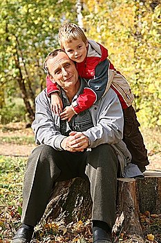 grandfather with the grandson sit in park  in autumn