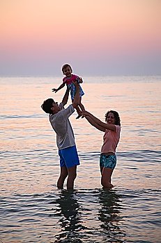 Daddy with mummy and child in sea on sunset