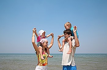 parents hold children on the shore of the sea