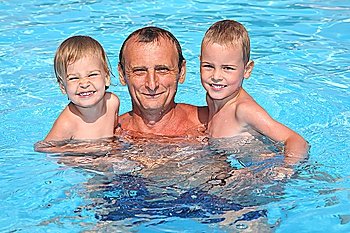 Grandfather holds grandsons on hands in pool