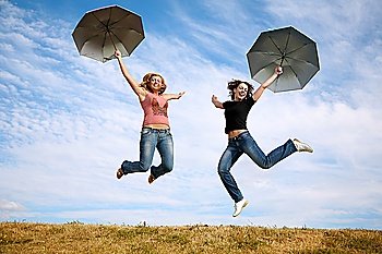 two young women jump with the umbrellas