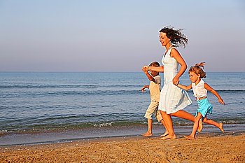 Mother with children running on edge of sea