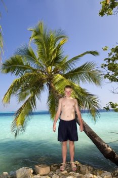 Teenager at palm tree and ocean in the background