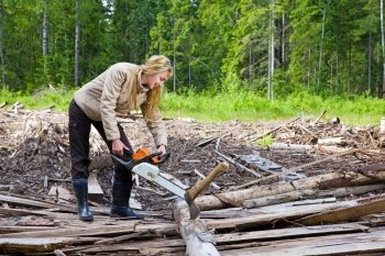 The young woman in wood saws a tree a chain saw  