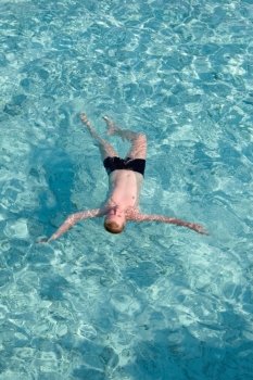 Maldives. The boy has a rest on transparent water of ocean  