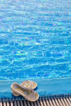 Slippers lies on the brink of pool  
