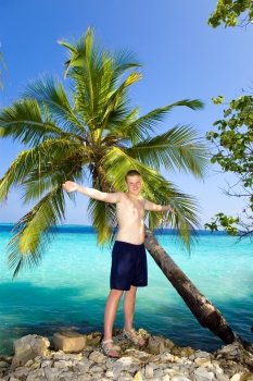 The happy teenager about a palm tree against ocean