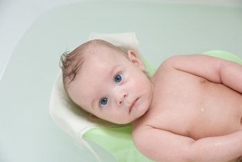 Beauty baby boy having bath at bathing stand