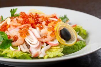 Salad with shrimps, caviar, calamaries, lettuce, lemon and olive