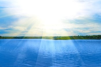 Lake, green field, sun and blue sky