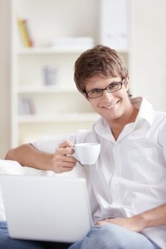 Attractive young man with a cup and laptop