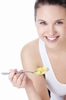 Young attractive woman holding a spoonful of corn flakes on a white background