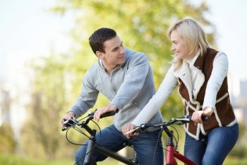Attractive couple on bicycles looking at each other