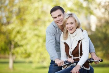 Laughing young couple on a bike outdoors