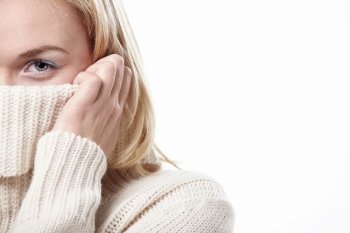 The woman closes the sweater face on a white background
