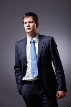 Young businessman in a business suit with a gray background