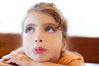 Blue eyes sad children girl crossed arms on table