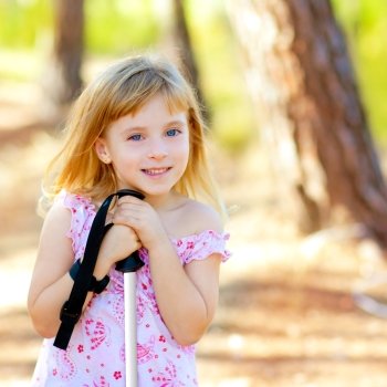 Beautiful kid girl in park forest smiling with hiking pole
