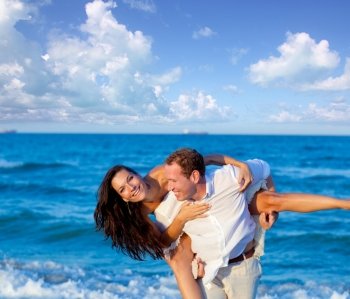 couple in love piggyback playing in a beach at blue Mediterranean