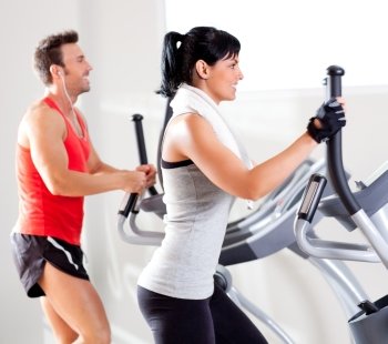man and woman with elliptical cross trainer in sport fitness gym club