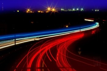 car light trails in red and white on night road curve