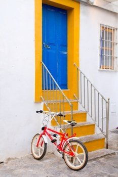 Ibiza white facade in blue door stairs and bicycle