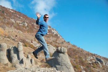 Man jumping on the rocks with landscape background