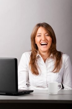 business laughing woman is sitting in the office with laptop