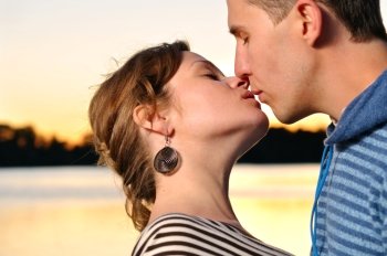 young attractive couple is kissing at sunset