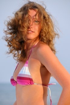 beautiful young woman with flying hair near the sea at sunset