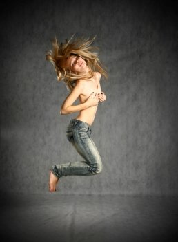 beautiful young blond woman in jeans jumping studio shot