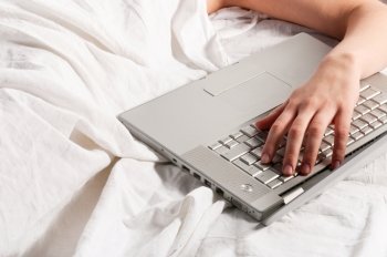 woman is lying in bed at morning with laptop