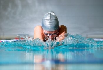 woman swims using the breaststroke in indoor pool