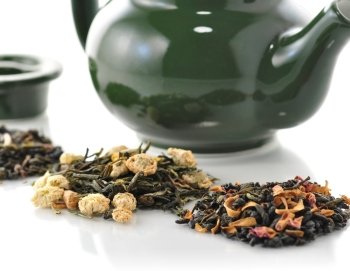teapot and variety of loose tea with fruits and flowers